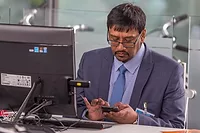 it-consultant-3726359_1920.jpg Man sits at computer facing camera