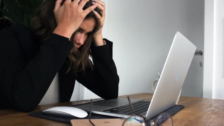 woman sitting at desk with head in hands