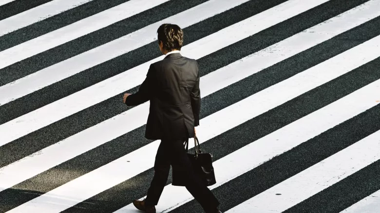 man in suit walking across crosswalk