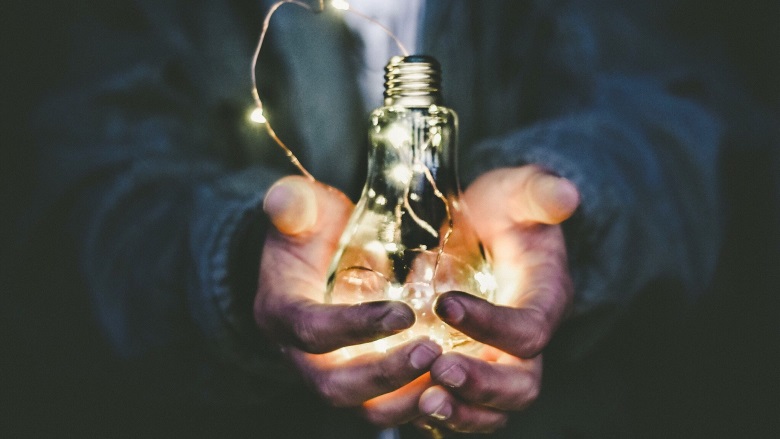 person in blue suit holding lightbulb with string lights