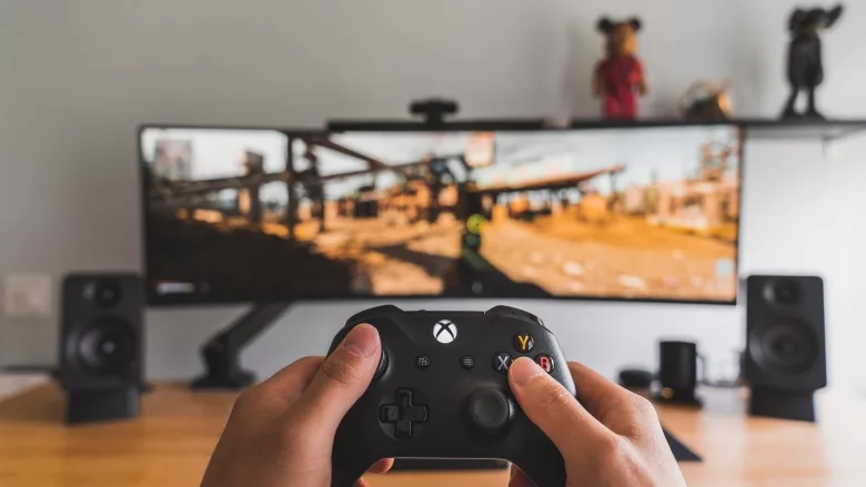 hands holding game controller in front of screen
