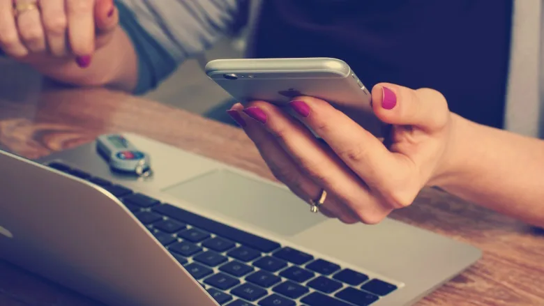 person holding their phone while using computer