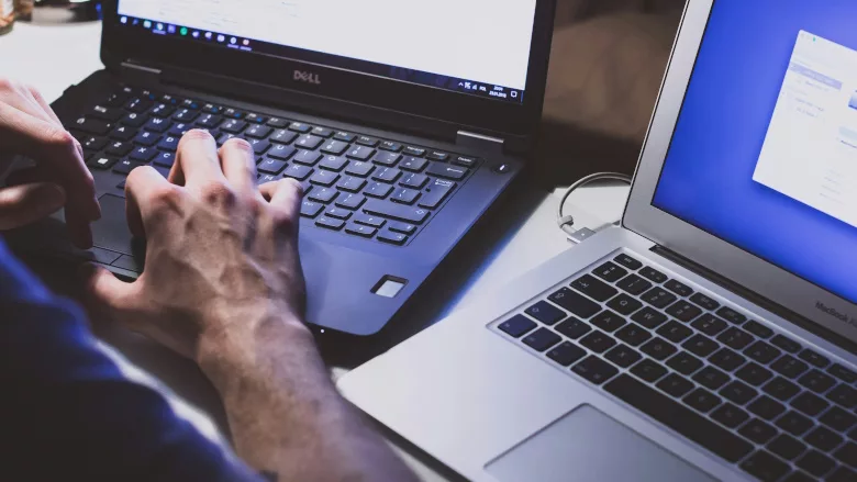 Person using two laptops