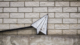 Paper airplane image against brick wall
