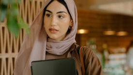 Woman holding laptop and wearing a hijab