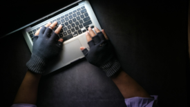 Gloved hands typing on a laptop