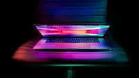 Partially closed laptop with pink screen Partially closed laptop with pink screen
