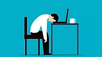 Person sitting at desk with head down on computer