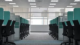 Two rows of black office chairs in blue cubicles