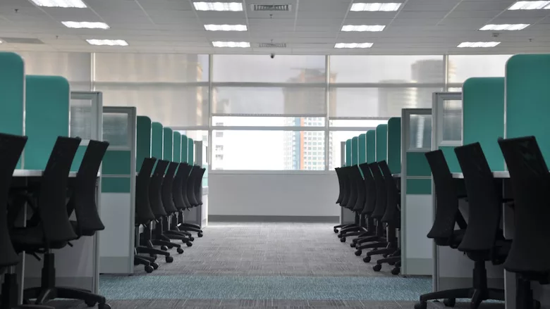 Two rows of black office chairs in blue cubicles