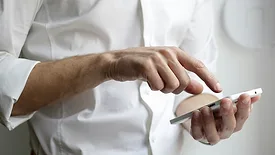 Man in white button down shirt holding white cell phone