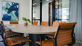 Conference table with brown chairs and large windows