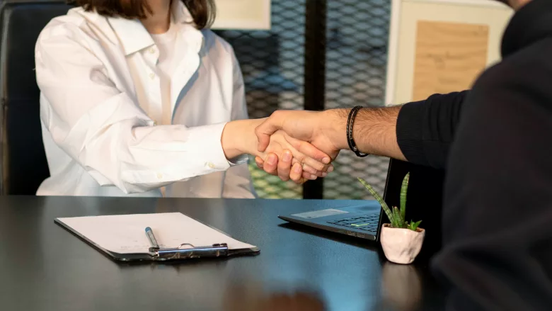Man and woman shake hands across table
