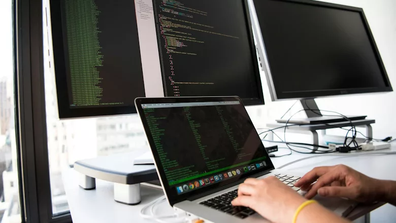 Person working on laptop and three monitors