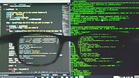 Glasses in front of coding on screen 