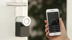 Person holding phone close to smart lock Person holding phone to smart lock