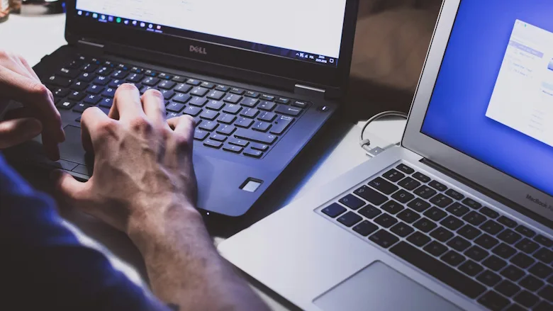 Person working on two laptops at the same time