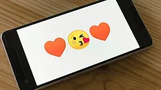 Phone showing hearts and flirty emojis