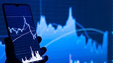 Person holding phone in front of stock market 