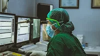 Healthcare worker wearing PPE using a computer Healthcare worker wearing PPE using a computer
