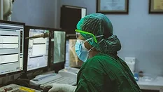 Healthcare worker wearing PPE using a computer