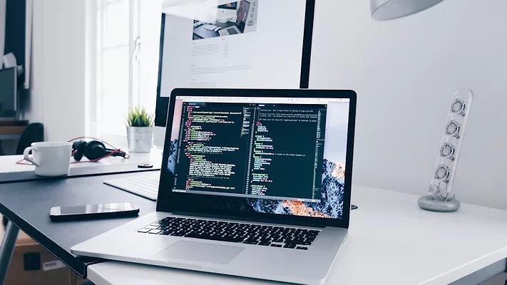 Open computer on white desk near window
