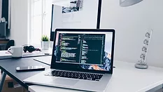 Open computer on white desk near window
