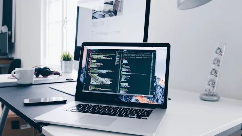 Open computer on white desk near window