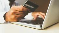 Person holding credit card while making purchase on a laptop Person holding credit card while making purchase on a laptop