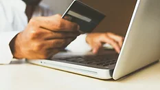 Person holding credit card while making purchase on a laptop