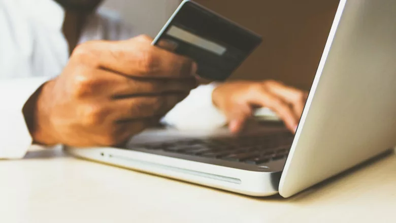Person holding credit card while making purchase on a laptop