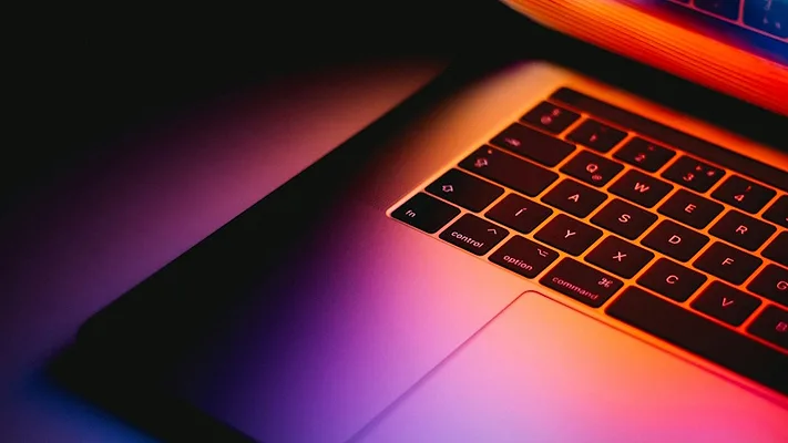 Open laptop with pink, orange, and purple lighting