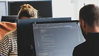 Two people working across from each other at shared workstation. Two people working across from each other at shared workstation.
