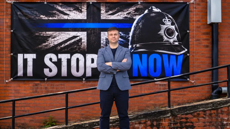 Paul Cooper in front of It Stops Now flag